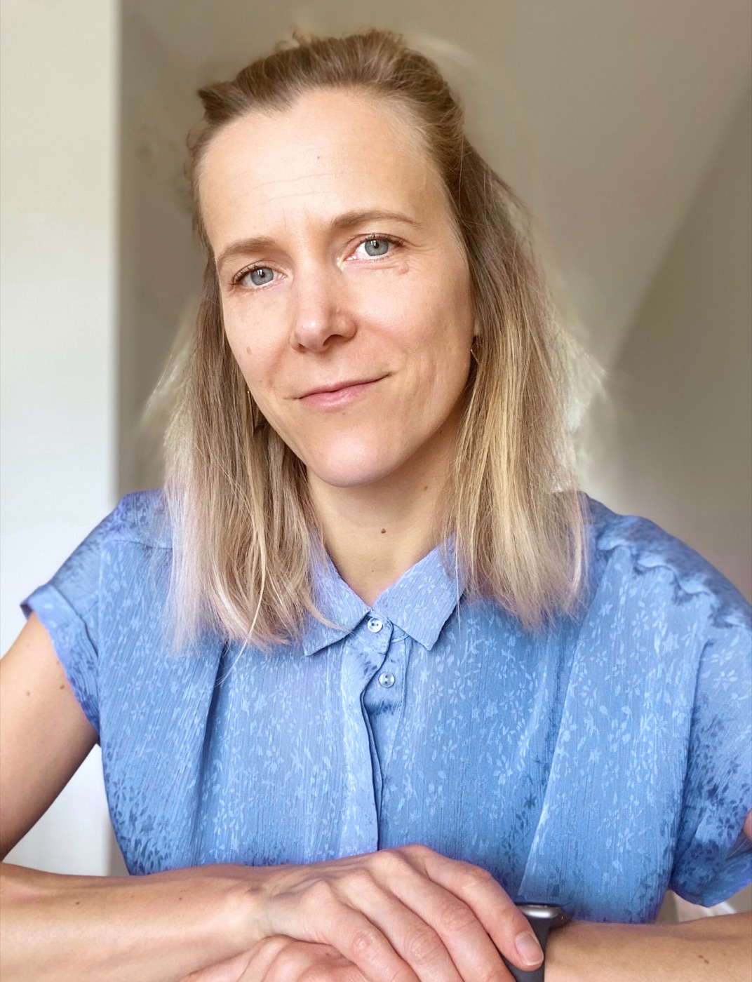 Portrait of Christin in a blue blouse, smiling into the camera